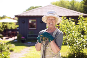 Happy Elderly Woman gardening in front of her home
