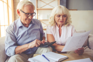 Elderly couple in their living room looking at financials and retirement house plans