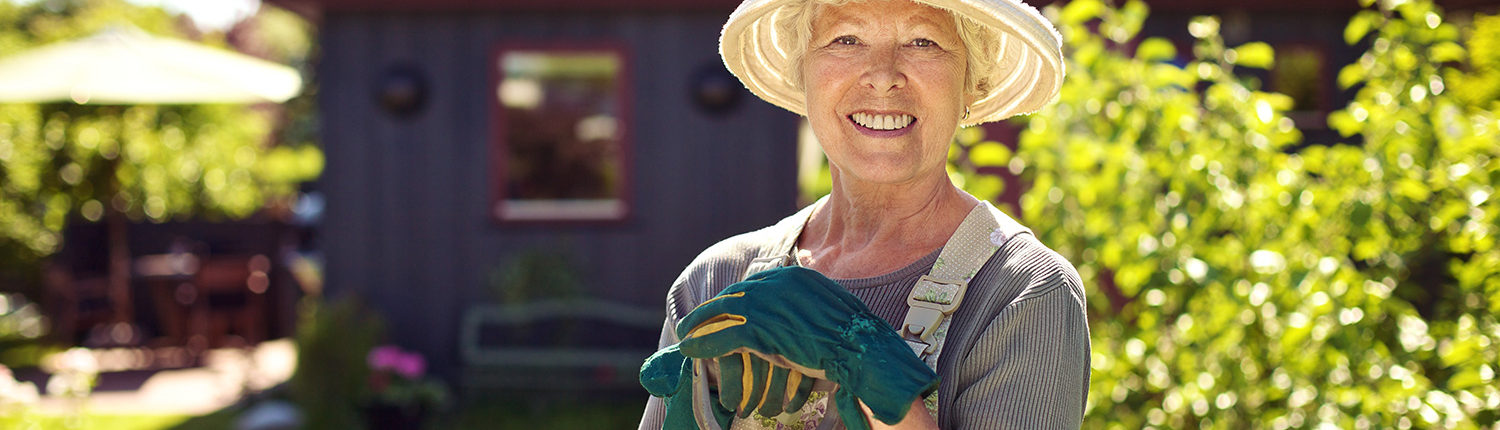 Happy Elderly Woman gardening in front of her home